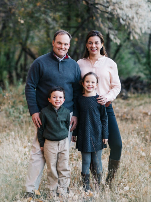 Family of 4 smiling outdoors