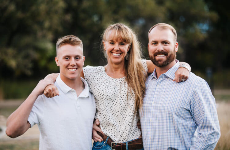 Family of 3 smiling outdoors