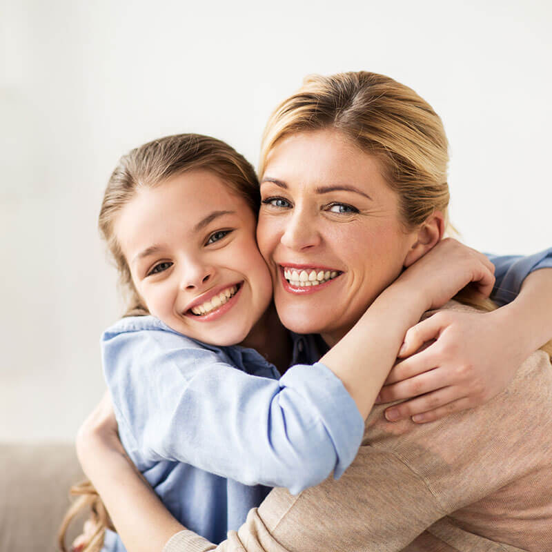 A mom and her young daughter smiling and hugging