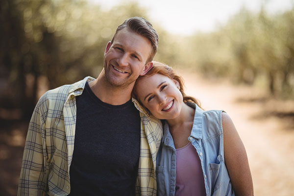 Middle-aged couple smiling and leaning their heads together outdoors
