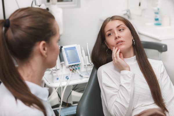 young brunette woman points out pain to dentist